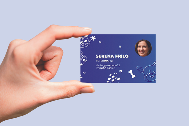 Hand holding blue UV business card for veterinarian Serena Frilo with animal illustrations and photo. Sprint24.